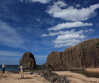 Sandy beach and dramatic sea cliffs with two people near Tango Onsen Hashiudosou Kyoto