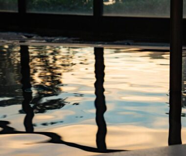 Indoor onsen pool with wooden pillars reflecting light at Tanoura Onsen Kaikatei Kawai Niigata