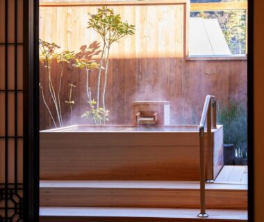 Steaming wooden soaking tub on deck framed by shoji door and small garden at Tateshina Shinyu Onsen Nagano