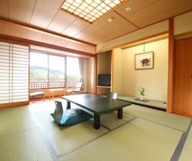 Spacious tatami room with low table, shoji doors opening to balcony and distant mountain views at Tateyama Prince Hotel