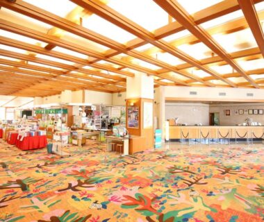 Spacious lobby with floral carpet, wooden beams, reception desk and gift display at Tateyama Prince Hotel in Nagano