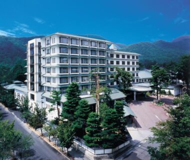 Multi-story hotel building with trees and mountain backdrop at Tateyama Prince Hotel in Nagano