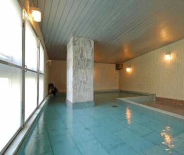 Spacious tiled indoor onsen with large windows and central pillar at Tatsumikan in Gunma, Kantō