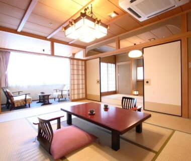 Traditional tatami room with low table, zabuton cushions, shoji screens and window seating at Tatsumikan, Gunma
