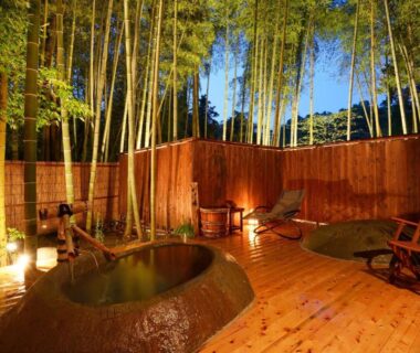 Outdoor stone onsen tubs on wooden deck with bamboo screening at Tatsuta Ryokan, Shizuoka