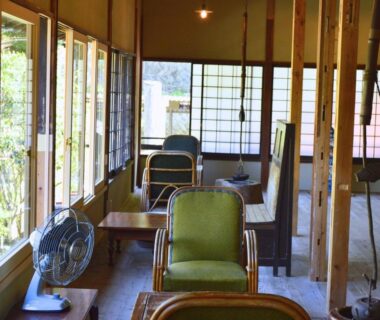 Wooden lounge with vintage chairs, shoji screens and fans at Tatsuta Ryokan in Shizuoka