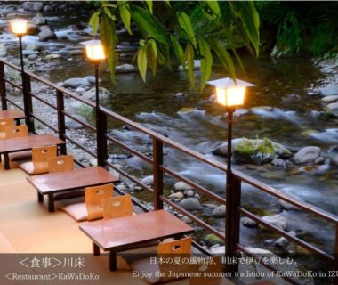 Low wooden tables and cushions on riverside terrace with lanterns at Tatsuta Ryokan in Shizuoka