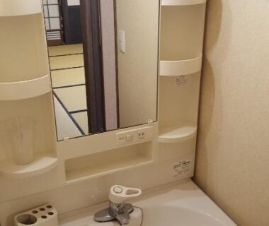 Compact wash basin with mirror reflecting tatami room and shoji sliding doors at Tawaraya Ryokan in Ōita, Japan