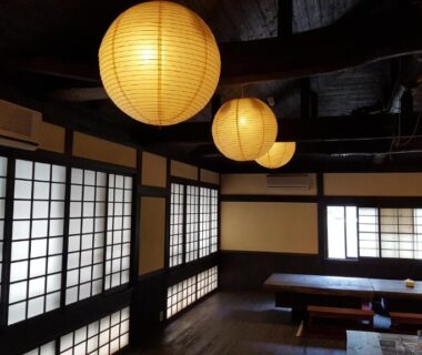 Shoji screens, round paper lanterns, exposed wooden beams and low seating in Tawaraya Ryokan common room, Oita, Kyushu