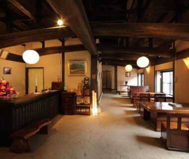Reception and seating area with exposed wooden beams and warm lantern lighting at Tawarayama Onsen Ryokan Minawa, Kumamoto
