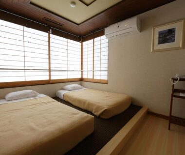 Simple tatami-style room with two low futons and shoji screens at Ryokan Tazuru Kyoto