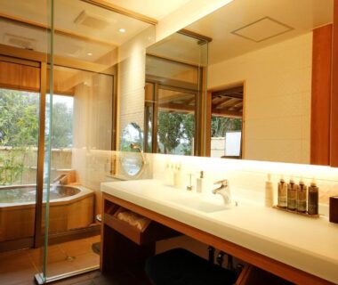 Spacious bathroom with wooden soaking tub, sink vanity, glass partition and garden view at Teisho Basaratei in Mie