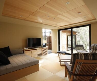 Spacious tatami room with low seating, wooden ceiling and sliding glass doors opening to greenery at Teisho Basaratei in Mie,