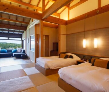 Spacious tatami room with twin beds, lounge area and exposed wooden beam ceiling at Teisho Basaratei in Mie, Kansai