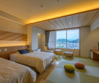 Twin beds in tatami-style room with low table and city view at Tendo Hotel, Yamagata