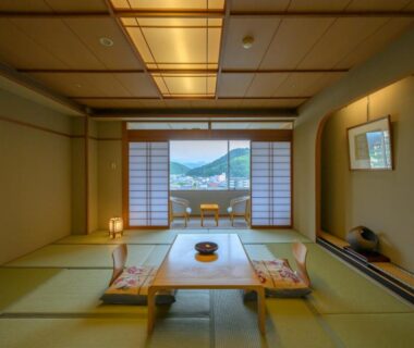 Traditional tatami room with low table, shoji screens and mountain and water view at Tendo Hotel in Yamagata