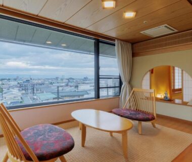 Tatami sitting area with low table, chairs and panoramic window overlooking Tendo town and surrounding hills