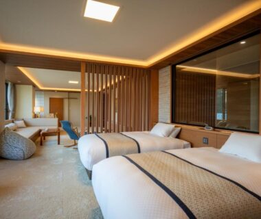 Spacious twin room with modern wooden screens and seating area at Tendo Onsen TAKINOYU, Yamagata