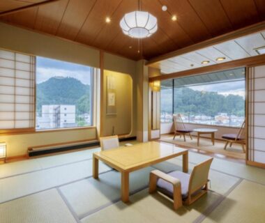 Spacious tatami room with low table, floor chairs, shoji screens and large windows overlooking mountains in Yamagata