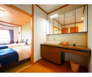 Twin bedroom with bedside lamps and sink area at Tenku Yubo Seikaiso in Ōita, Kyūshū