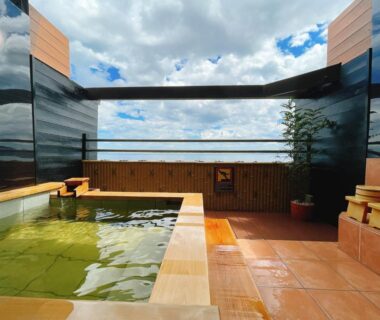 Rooftop open-air onsen bath with wooden edging and sky view at Tenku Yubo Seikaiso in Ōita