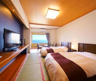 Tatami room with twin beds, low TV and large window at Tenku Yubo Seikaiso in Ōita, Japan