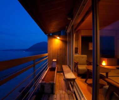 Evening wooden veranda with benches overlooking coastal waters, interior tatami seating visible at Tenku Yubo Seikaiso, Ōita