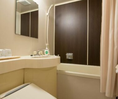 Compact bathroom with bathtub, toilet, sink and mirror at Tenpyo Ryokan Nara