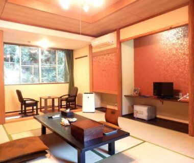 Traditional tatami room with low table, floor cushions, chairs and a window showing greenery