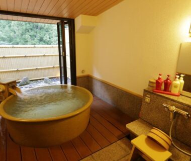 Room with wooden round onsen bath, shoji doors opening to bamboo garden