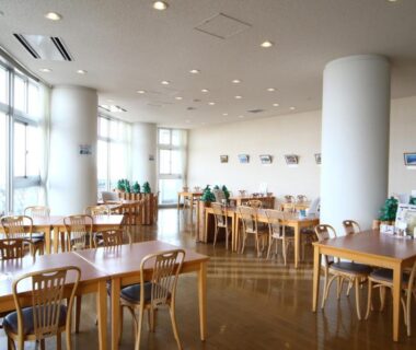 Spacious sunlit dining area with wooden tables at Teshio Onsen Yubae, Hokkaidō