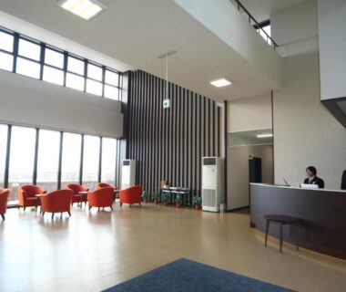 Airy reception lounge with orange chairs and windows at Teshio Onsen Yubae, Hokkaidō, Japan