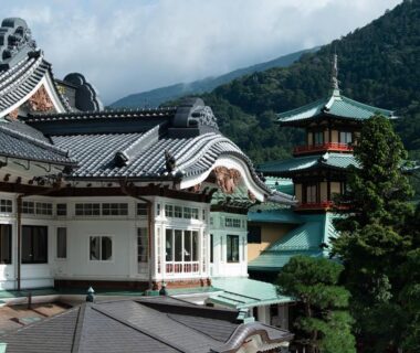 Decorative tiled roofs and ornate gables of The Fujiya Hotel with tree-lined mountain backdrop in Kanagawa