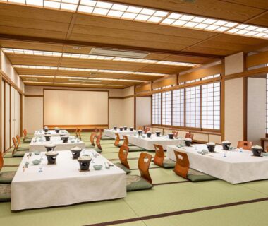 Large tatami banquet hall with low tables and wooden backrest chairs and shoji screens at The Gran Resort Elegante Atami