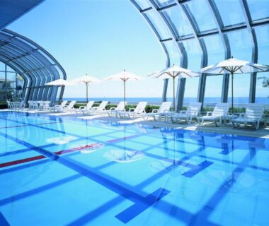Indoor glass-roof pool with lounge chairs and parasols at The Gran Resort Elegante Awajishima, Hyōgo, Japan