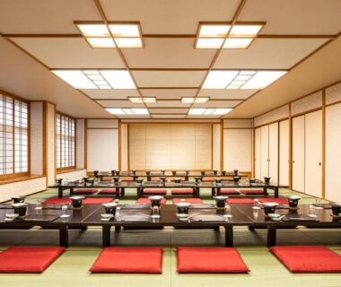 Large tatami banquet room with low tables and red floor cushions at The Gran Resort Kinosaki, Hyōgo