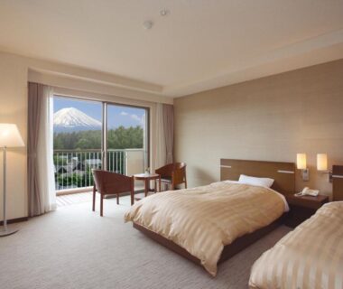 Spacious twin room with balcony, seating area and distant mountain view at The Gran Resort Princess Fujikawaguchiko Yamanashi