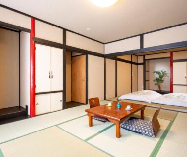 Traditional tatami room with low table, floor futon and sliding panels at The RYOKAN O in Gifu