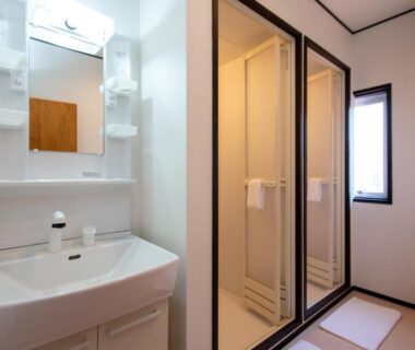 Bright ryokan bath area with sink, mirror cabinet, shower stalls and small window at The RYOKAN O Gifu