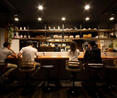 Bar counter with seated guests and shelves at The RYOKAN O in Gifu, Chūbu