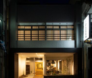 Lit ryokan entrance with visible lobby and second-floor shoji windows in Gifu, Chūbu, Japan