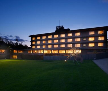 Dusk view of illuminated ryokan facade with lawn and pathway at Toba International Hotel Shiojitei Mie