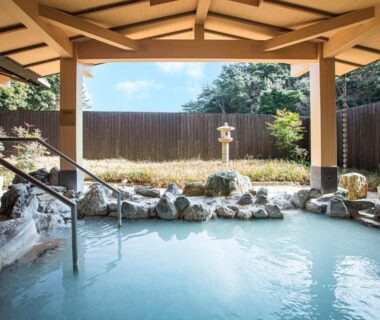 Sheltered hot spring bath with stone lantern, rock edging and garden fence at Toba International Hotel Shiojitei in Mie