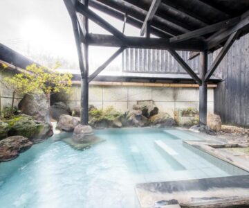 Covered onsen bath with wooden beams and rock edging at Tofuya Ryokan, Onogawa Onsen, Yamagata