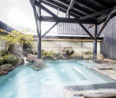 Covered onsen bath with wooden beams and rock edging at Tofuya Ryokan, Onogawa Onsen, Yamagata
