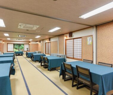 Long tatami dining room with blue-tablecloth tables, low chairs, shoji screens and garden view at Togakubo, Kanagawa