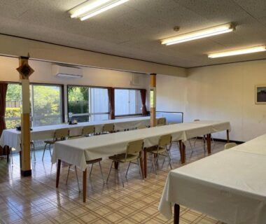 Long communal dining room with white tablecloths on tables and chairs at Togawaso in Yamanashi, Chubu, Japan