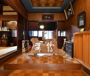 Genkan with polished hardwood floor, raised tatami room, shoji screens and wooden reception counter at Togiso in Ishikawa