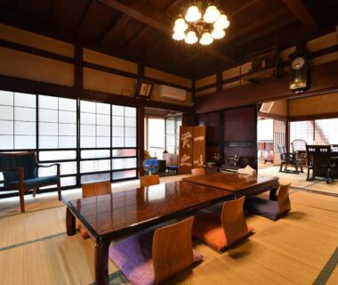 Spacious tatami dining room with low wooden table, zaisu chairs and shoji screens at Togiso in Ishikawa