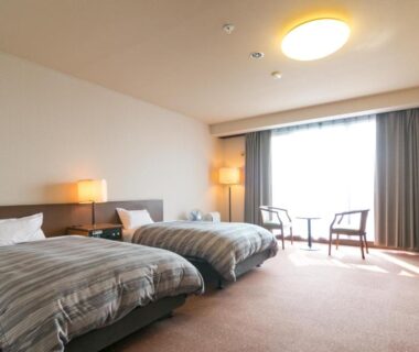 Spacious twin room with two beds, seating area and large window at Tokachi Makubetsu Onsen Grandvrio Hotel Hokkaidō